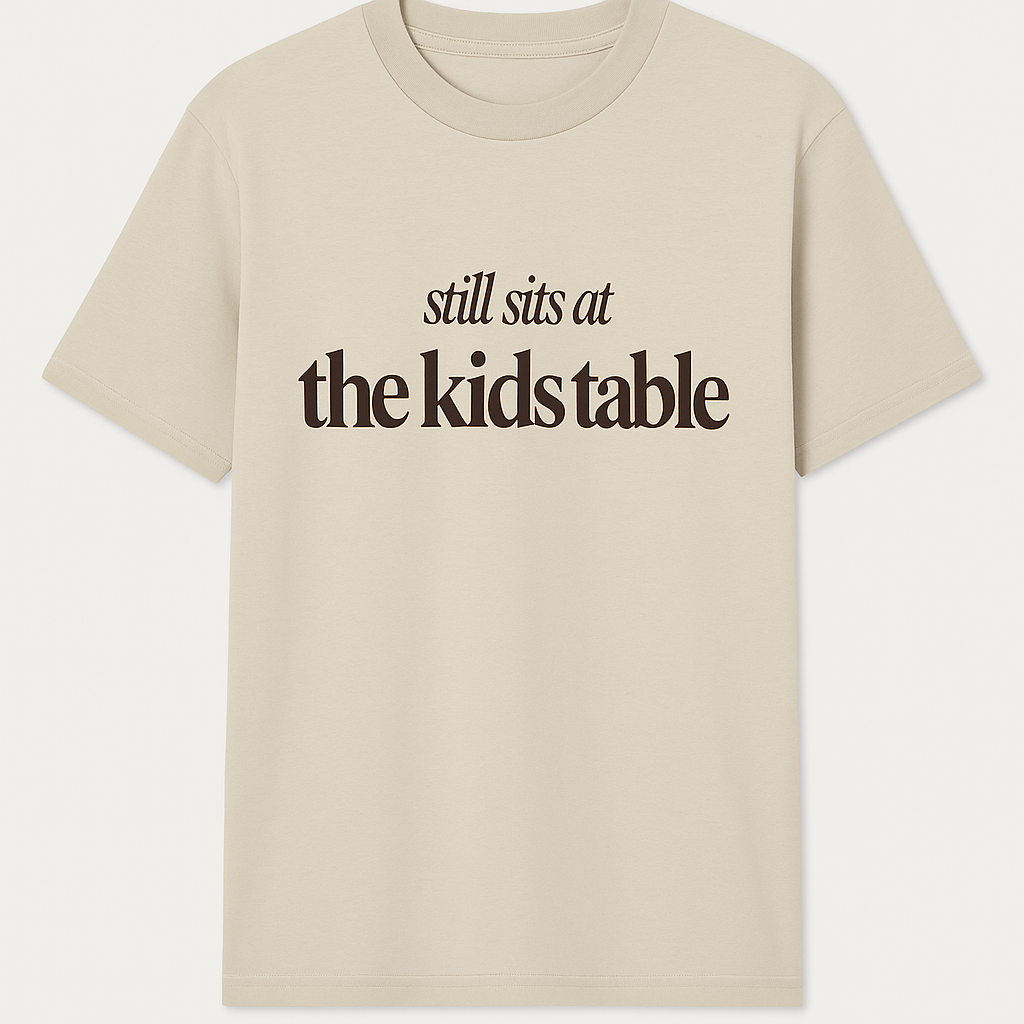 Tan “Still Sits at the Kids Table” Thanksgiving Oversized Tee – Soft Drop-Shoulder Unisex Shirt