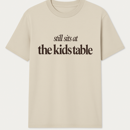 Tan “Still Sits at the Kids Table” Thanksgiving Oversized Tee – Soft Drop-Shoulder Unisex Shirt